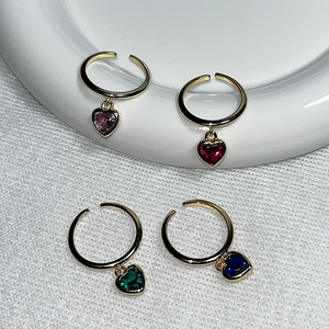 Detailed shot of four gold adjustable rings with heart-shaped colorful zircon pendants