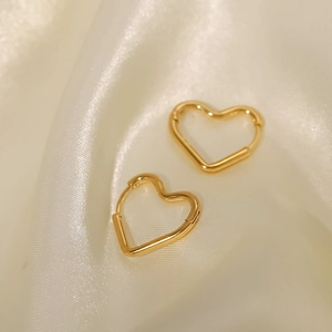 Macro shot of 18K gold plated heart earrings on white silk fabric background