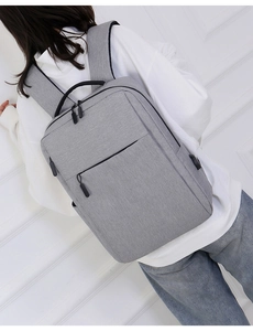 Minimalist grey business laptop backpack with USB charging port shown on a model back