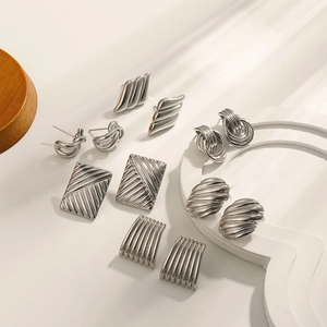 Set of modern silver 18K plated twisted stripe and geometric earrings on beige surface
