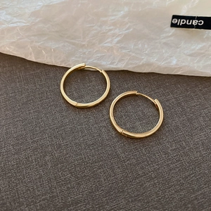 Minimalist small geometric gold hoop earrings with polished finish on textured background