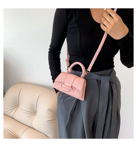 Detail of pink lychee grain leather mini bag worn by model with ring buckle closure