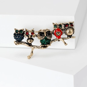 Vintage owl branch brooch with colorful crystals and enamel on a white display pedestal