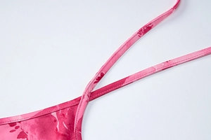 Detail of pink floral print dress showing smooth fabric texture and fine strap design