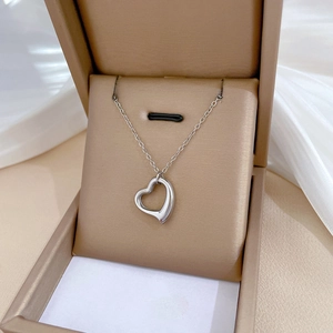 Detailed view of silver heart pendant necklace on soft fabric jewelry display
