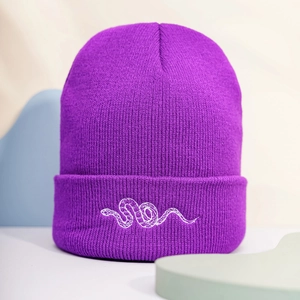 Detail of purple ribbed knit beanie with white snake embroidery on the folded cuff
