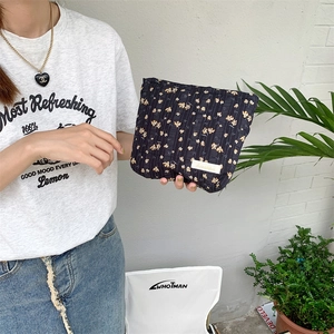 Close-up of floral canvas cosmetic bag with navy blue base and yellow flower patterns