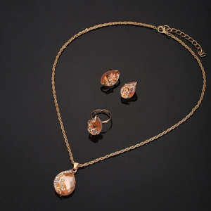 Detailed close-up of golden jewelry set with orange pear-cut crystals and rhinestones