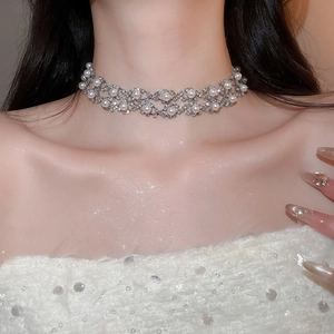 Detail of silver choker necklace with shimmering rhinestones and elegant pearls on model