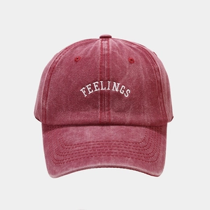 Close-up of white FEELINGS embroidery on vintage washed burgundy cotton baseball cap