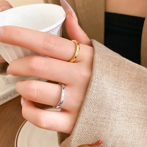 Detail of star-engraved rings with colored zircons worn while holding a coffee cup