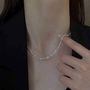 Detailed close-up of a shimmering silver cuban chain necklace worn with a black suit jacket
