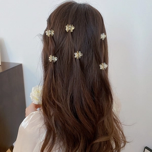Detail of six transparent floral hair claws with pearls styled on wavy brown hair