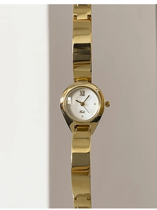 Macro shot of elegant gold bangle watch with white dial and Roman numerals XII
