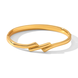 Detail of minimalist 18k gold plated titanium steel knot bangle with mirror finish