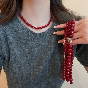 Detail view of dark red glass beads necklace with a silver oval metal clasp on a model