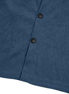 Detailed close-up of blue corduroy fabric texture with black round snap buttons