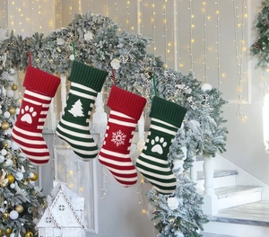 Set of 4 knitted Christmas stockings with snowflake patterns hanging on festive stairs