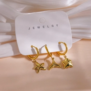 Detailed shot of three 14K gold plated earrings with starfish, whale tail and star charms