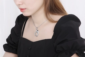 Close-up of a silver hollow heart-shaped stainless steel pendant worn by a model