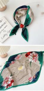 Detailed plissé texture of green floral scarf with pleated silk-like fabric detail