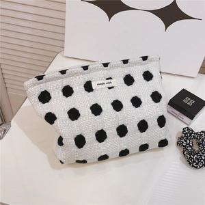 Détails d'une trousse à maquillage tissée blanche à pois noirs avec étiquette en tissu