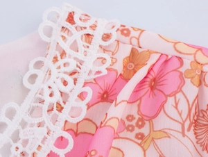 Dettaglio di chiffon floreale con delicato pizzo bianco sul bordo dell'abito a balze