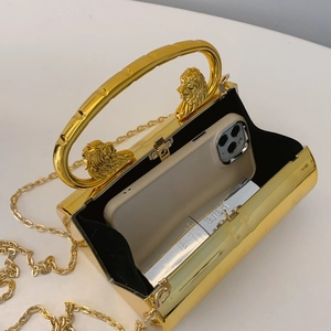 Golden evening clutch with lion head handle and metal chain on white background