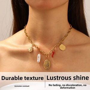 Dettaglio della collana dorata con ciondolo sole e perla indossata dal modello