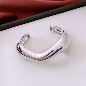 Detailed close-up of a silver irregular polished cuff bracelet with a liquid metal texture