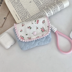 Macro view of blue quilted floral storage pouch with pink heart button and woven lanyard