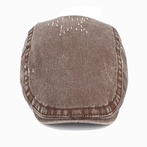 Détail de la broderie étoile sur denim marron et texture délavée de la casquette plate