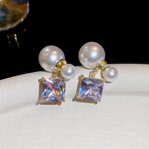 Macro detail of 18k gold plated square purple zircon and double pearl drop earrings