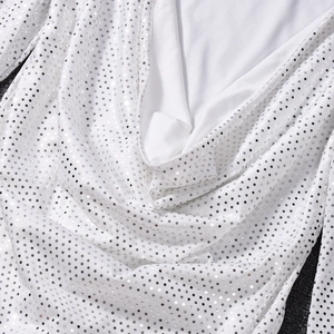 Gros plan d'une robe blanche montrant des paillettes argentées et le tissu dense