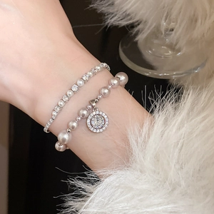Double-layer pearl bracelet with zircon halo pendant on a soft white faux fur background