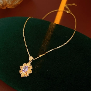 Macro shot of vintage golden pendant with oval purple gemstone on green velvet