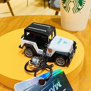 Close-up of black and white police car keychain with small bell and 911 decals