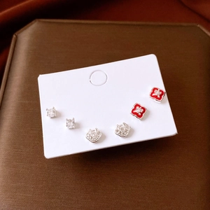 Detail of silver stud earring set with zircon flower and ruyi lock on display card