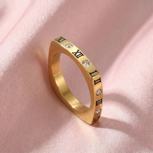 Gros plan d'une bague dorée en acier inoxydable avec chiffres romains et oxydes de zirconium