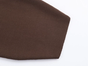 Dettaglio macro della trama in maglia marrone scuro e cuciture lisce sul polsino