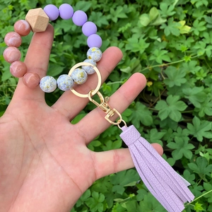 Handheld beaded keychain bracelet with purple tassels and peach gold foil beads