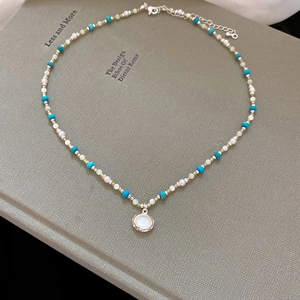 Dettaglio della collana di perle blu con pendente ovale su un libro verde raffinato