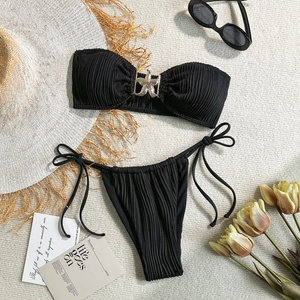 Flat lay of black ribbed bikini with golden starfish hardware and beach accessories