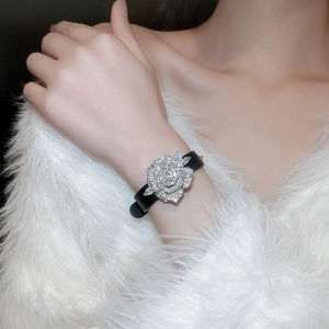 Detail der funkelnden, diamantbesetzten Silberblume auf einem schwarzen Armband