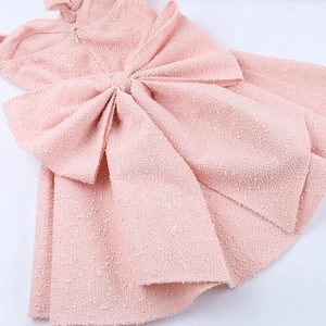 Detail showing pink tweed texture with back zipper and large decorative bow on the dress