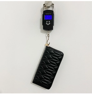 Black quilted PU leather long wallet shown on a digital scale weighing approximately 150g