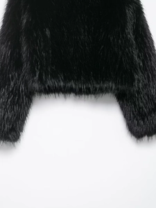 Close-up of the plush texture and hem detail on a black faux fur cropped jacket