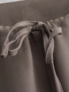 Macro view of taupe drawstring waist design and tied bow detail on casual pants