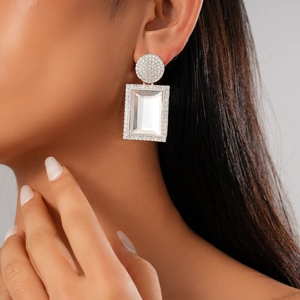 Dettaglio di orecchini geometrici in argento con cristalli e pavé indossati dalla modella