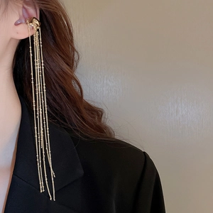 Close-up of golden multi-layer tassel ear cuff with delicate hanging chains on ear